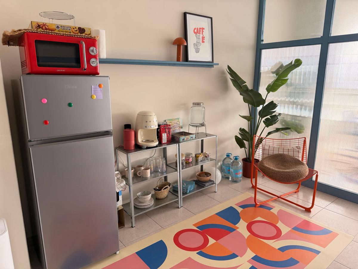 Rincón de cocina y café con nevera, plantas y alfombra de colores