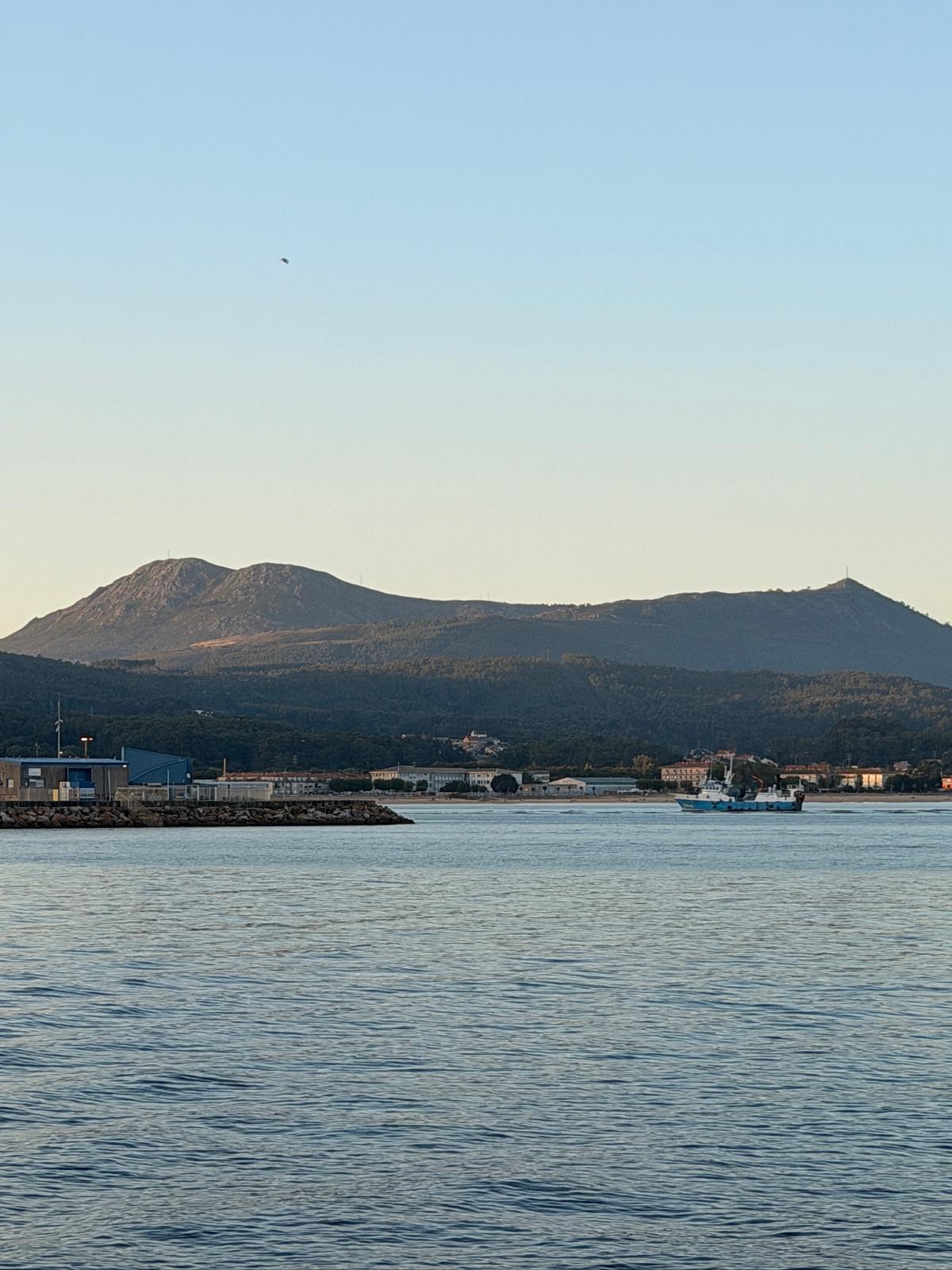 La bahía de Ribeira al atardecer con un barco pesquero entrando a puerto