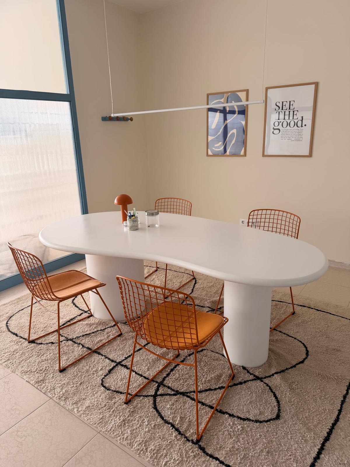 Sala de reuniones con mesa blanca orgánica y sillas naranjas